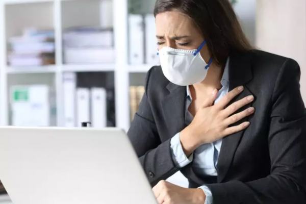 Woman in a mask clutching her chest